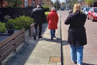 Een cameravrouw filmt twee mensen die op straat wandelen
